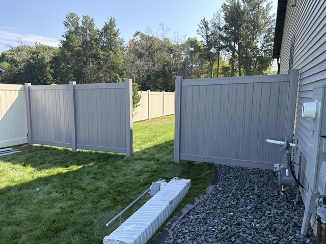 Gray vinyl privacy fence and gate installed beside Chippewa Falls home